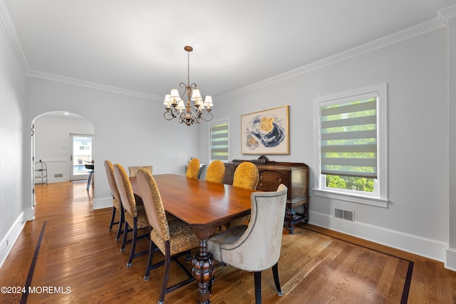 dining room with hardwood / wood-style flooring, plenty of natural light, ornamental molding, and a notable chandelier