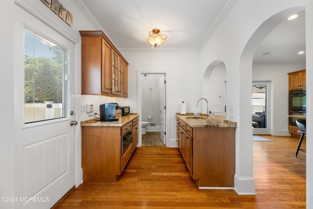 kitchen featuring light hardwood / wood-style floors, light stone countertops, ornamental molding, and sink