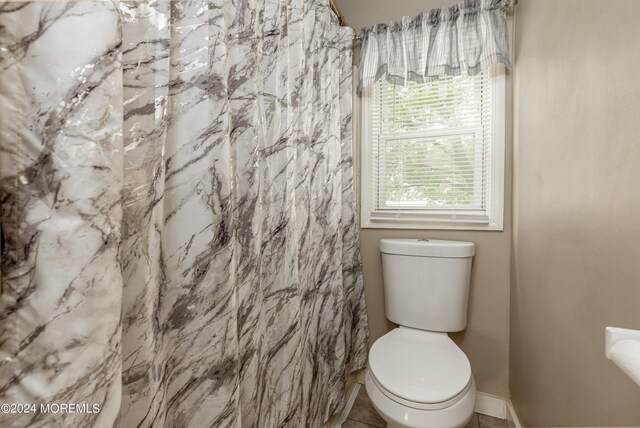 bathroom featuring toilet, walk in shower, and tile patterned floors