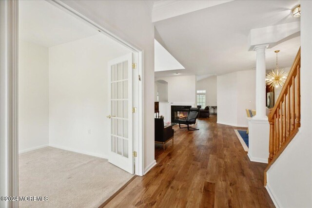 hallway with lofted ceiling, hardwood / wood-style floors, and ornate columns