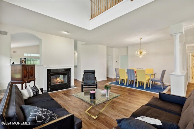 living room featuring a premium fireplace, vaulted ceiling, wood-type flooring, and ornate columns