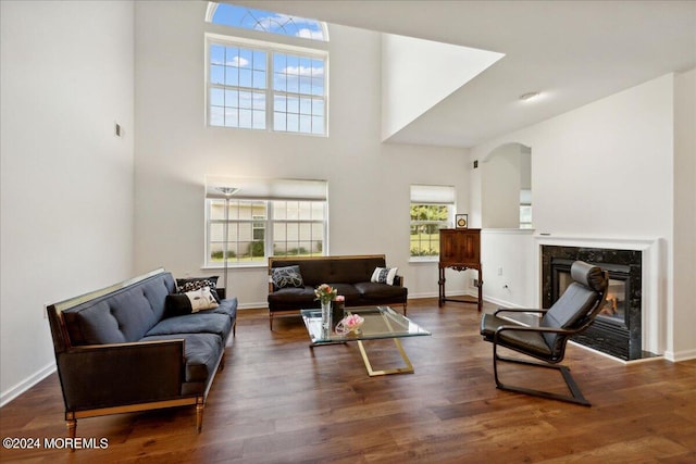 living room with a premium fireplace, a high ceiling, and dark hardwood / wood-style flooring