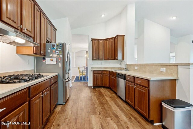 kitchen with lofted ceiling, stainless steel appliances, light hardwood / wood-style floors, and sink