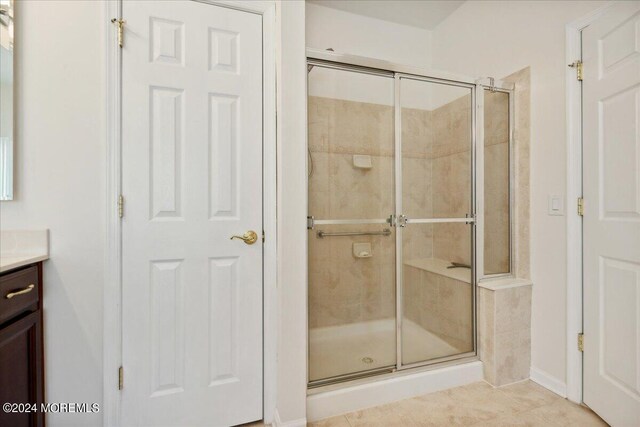 bathroom with a shower with door, vanity, and tile patterned flooring