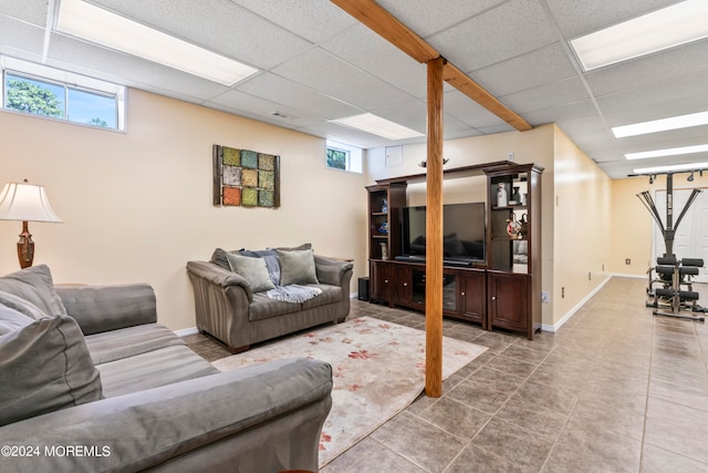 living room featuring a drop ceiling, tile patterned floors, and a wealth of natural light