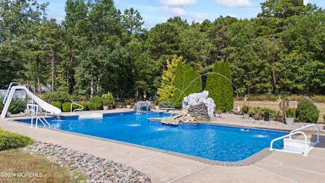 view of pool featuring a water slide, pool water feature, and a patio area