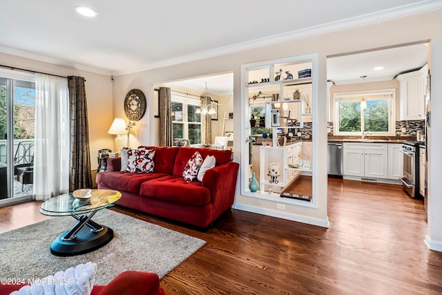 living area with baseboards, dark wood finished floors, recessed lighting, crown molding, and a notable chandelier