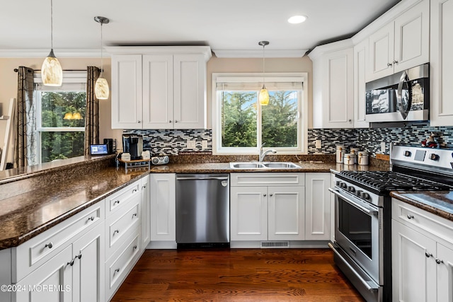 kitchen featuring a peninsula, a sink, appliances with stainless steel finishes, crown molding, and a wealth of natural light