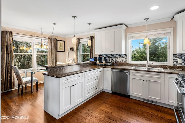 kitchen featuring visible vents, a sink, appliances with stainless steel finishes, a peninsula, and crown molding