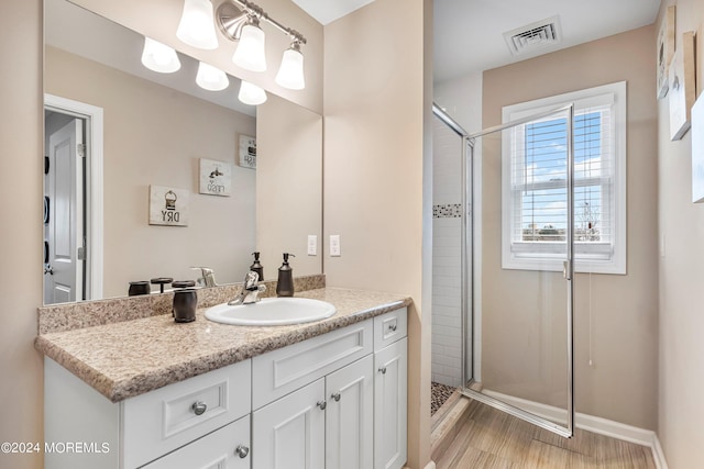 bathroom with visible vents, a stall shower, wood finished floors, baseboards, and vanity