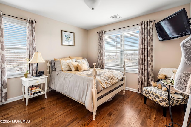 bedroom with dark wood-style floors, visible vents, and baseboards