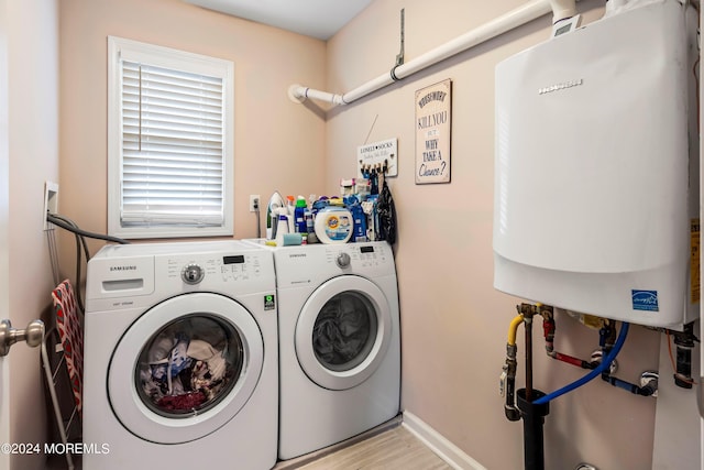 laundry area with tankless water heater, baseboards, washing machine and dryer, and laundry area