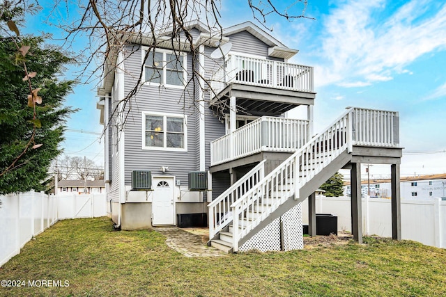 back of property with a deck, stairway, a lawn, and a fenced backyard