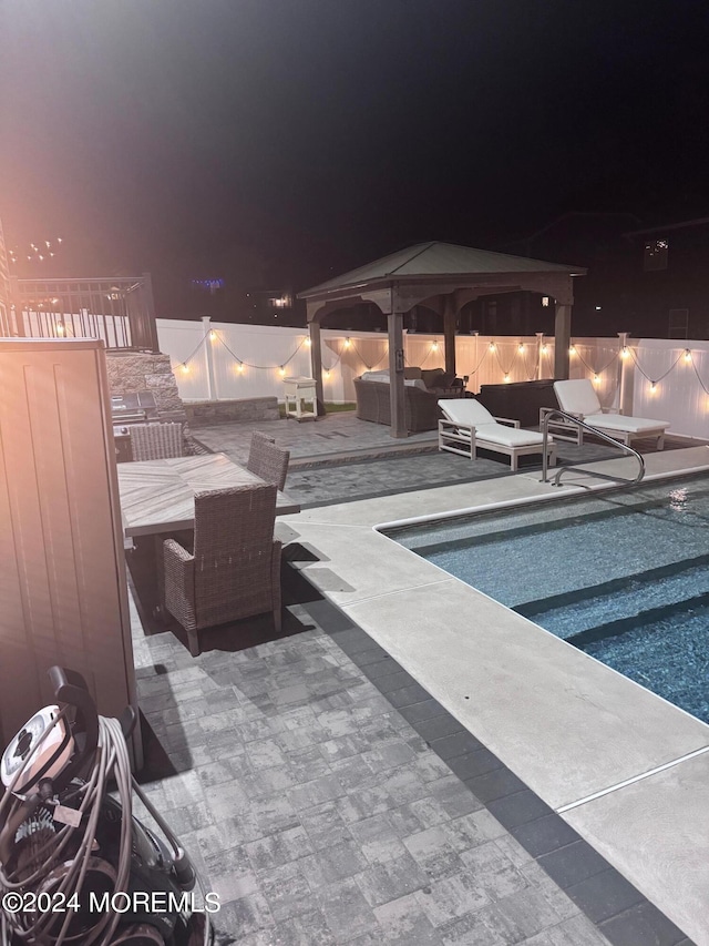 pool at twilight featuring a patio, outdoor lounge area, and a gazebo