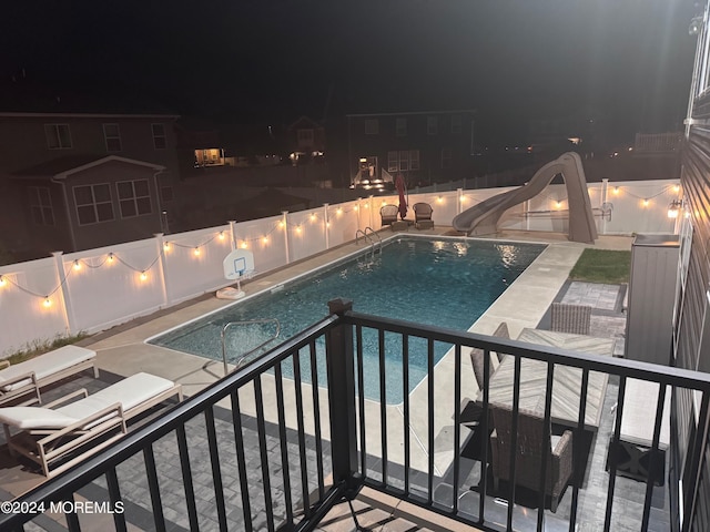 pool at twilight featuring a water slide and a patio area