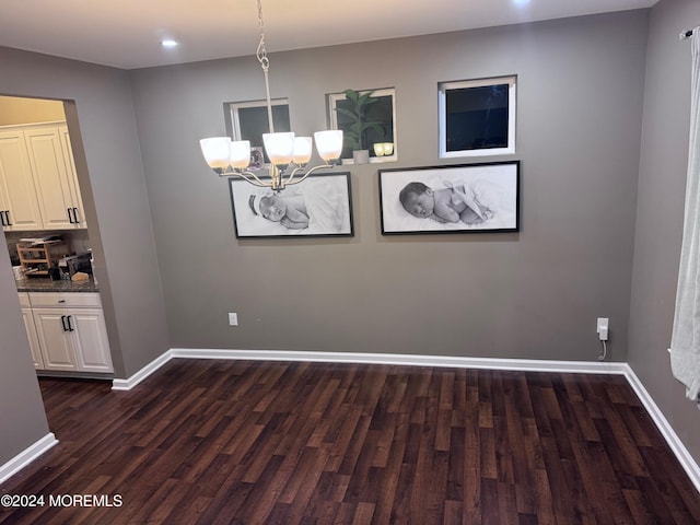 unfurnished dining area featuring an inviting chandelier and dark hardwood / wood-style flooring