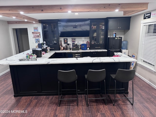 kitchen with black fridge, a large island with sink, and dark hardwood / wood-style floors