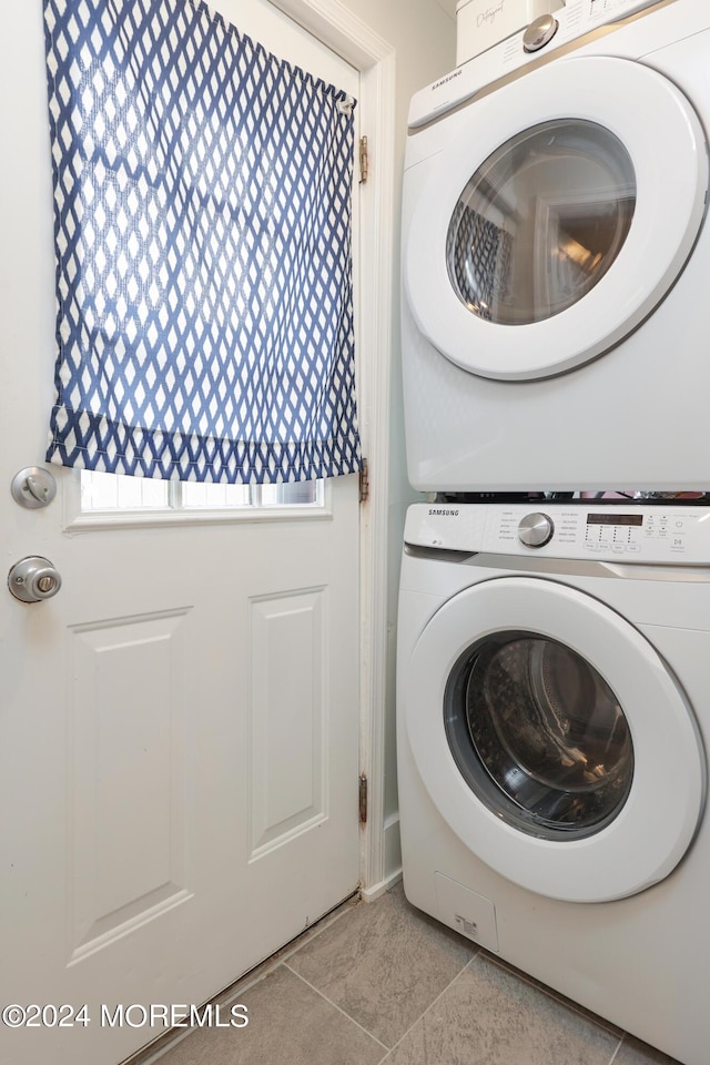 washroom featuring plenty of natural light, light tile patterned flooring, and stacked washer and clothes dryer