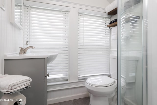 bathroom featuring a shower with door, vanity, and toilet