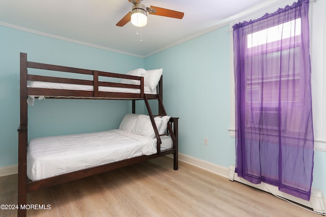 bedroom featuring ceiling fan, crown molding, a baseboard heating unit, and light wood-type flooring