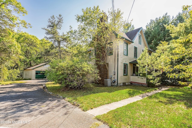 view of front of house with central AC, a front yard, and a garage