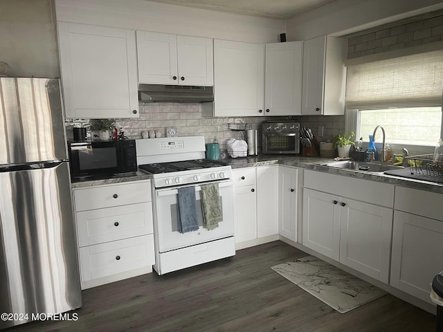 kitchen featuring white range with gas stovetop, white cabinets, stainless steel fridge, and sink