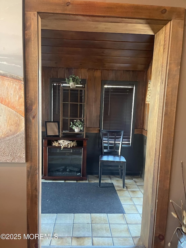 doorway to outside with tile patterned floors and wooden walls