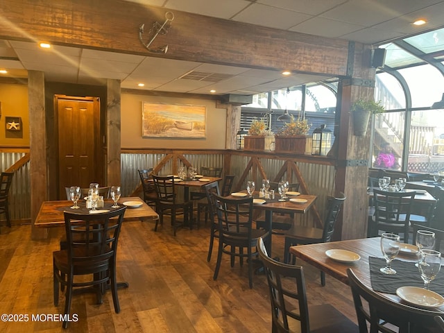 dining space with a drop ceiling and wood-type flooring