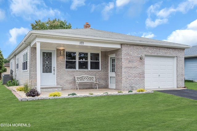 view of front of home featuring cooling unit, a garage, covered porch, and a front yard