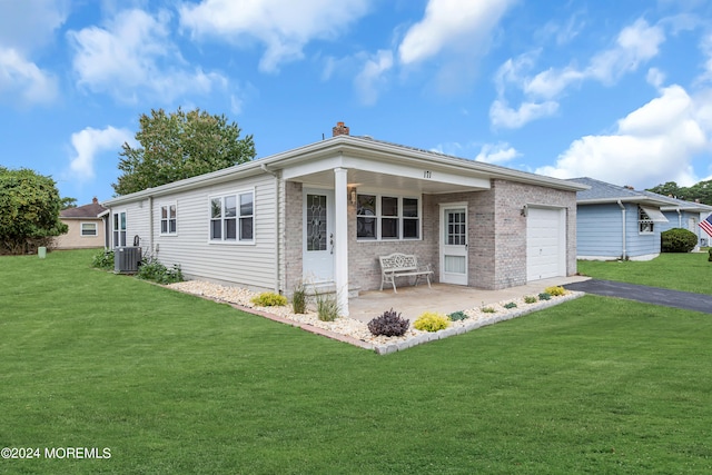 view of front of house featuring cooling unit, a garage, and a front lawn