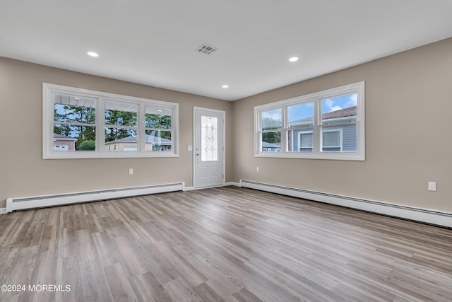 spare room featuring a baseboard radiator, light hardwood / wood-style floors, and a wealth of natural light