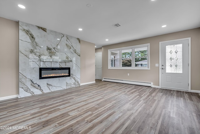 unfurnished living room featuring a baseboard radiator, light hardwood / wood-style floors, and a premium fireplace