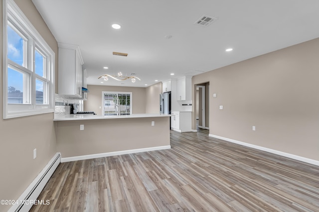 kitchen featuring white cabinets, stainless steel fridge, kitchen peninsula, a baseboard heating unit, and light wood-type flooring