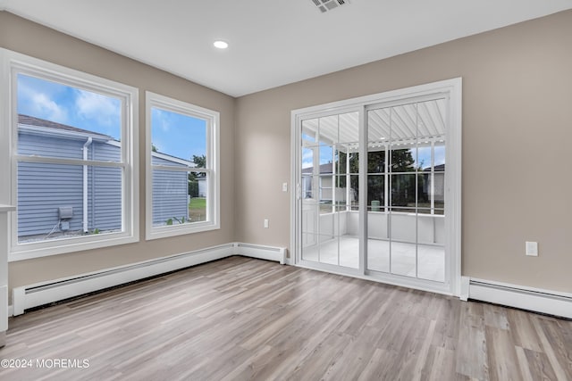 unfurnished room featuring light wood-type flooring and a baseboard heating unit