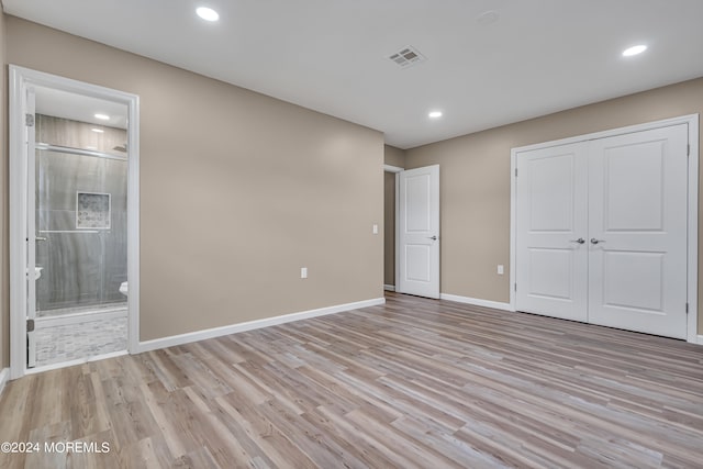 unfurnished bedroom featuring light hardwood / wood-style flooring, connected bathroom, and a closet