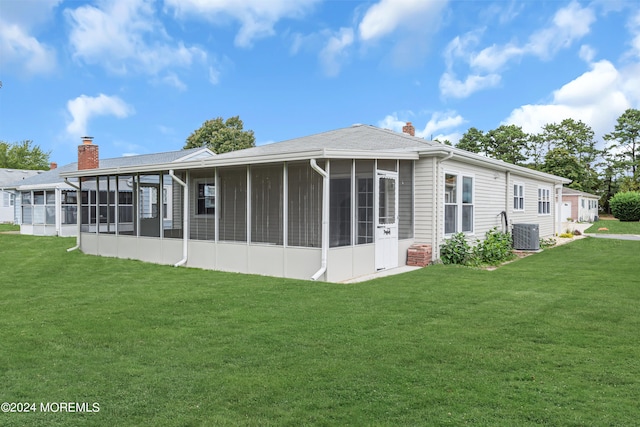 rear view of property with a lawn, central AC, and a sunroom