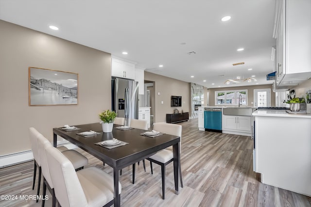 dining space with light wood-type flooring, sink, and a baseboard heating unit