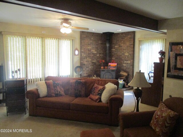 living room with ceiling fan, plenty of natural light, carpet flooring, and a wood stove