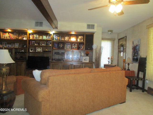 carpeted living room with ceiling fan and beamed ceiling