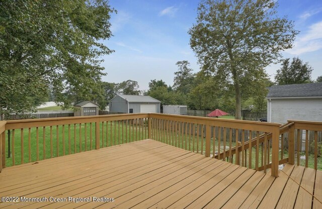 wooden terrace featuring a storage unit and a lawn