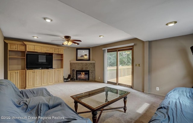 living area featuring baseboards, light colored carpet, ceiling fan, and a fireplace