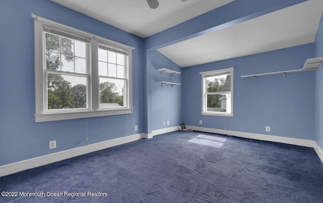 empty room with carpet flooring, baseboards, and vaulted ceiling