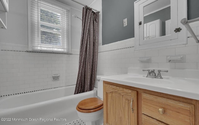 bathroom with toilet, tile walls, vanity, and shower / bath combination with curtain