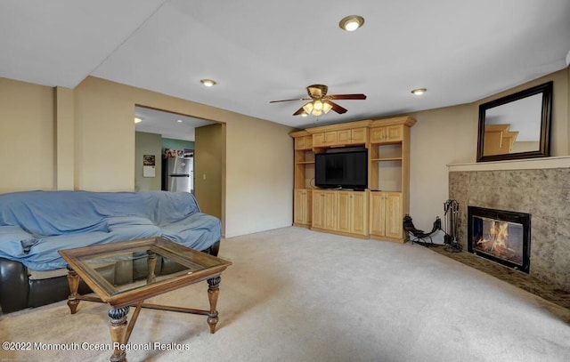 living room with a ceiling fan, a fireplace, and light colored carpet