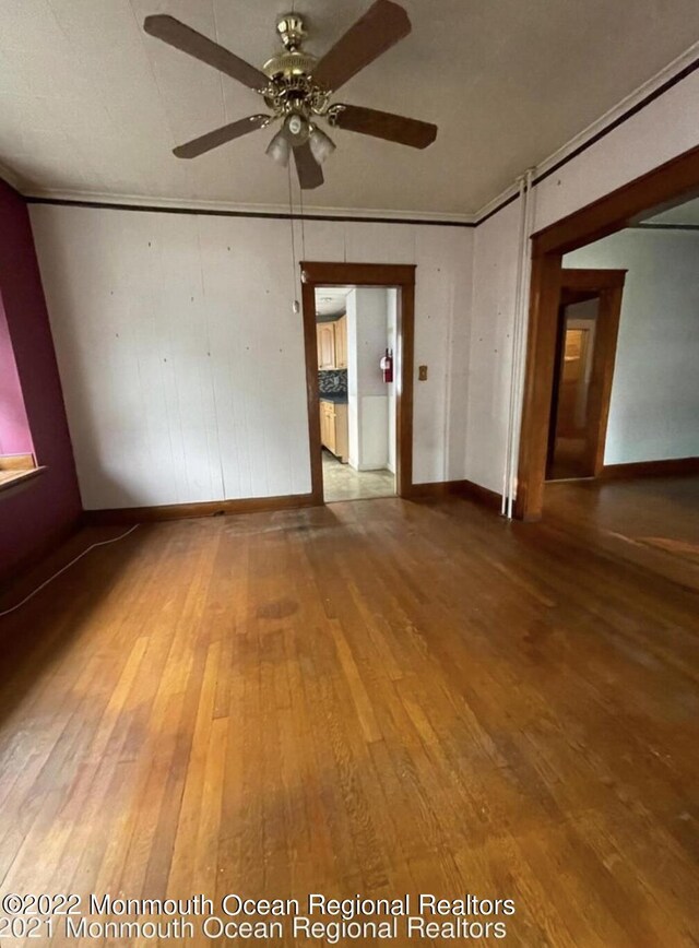 spare room with ceiling fan, wood-type flooring, and ornamental molding