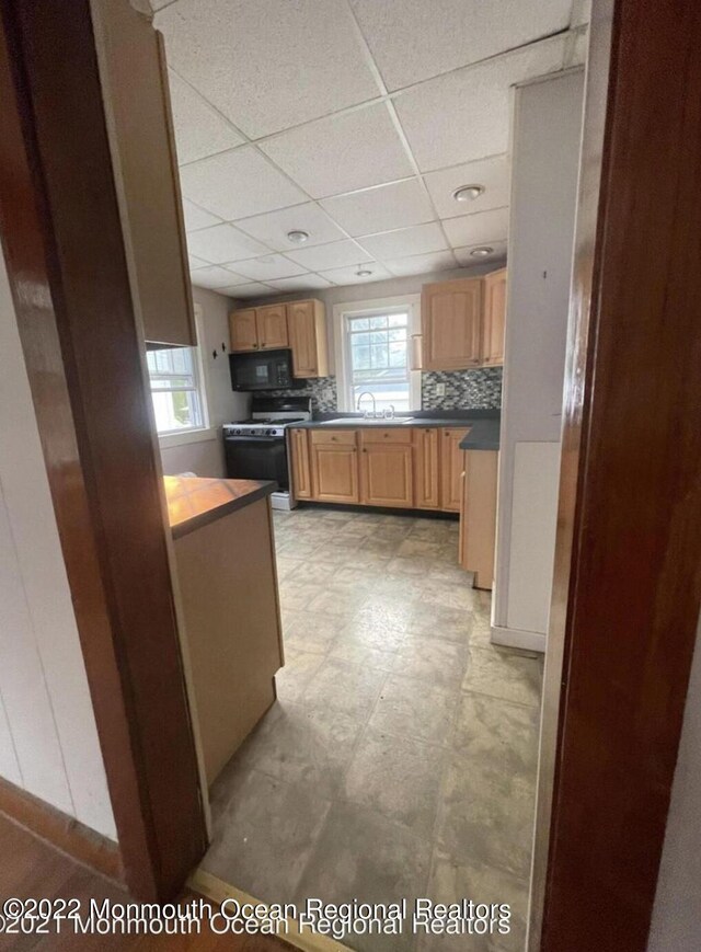 kitchen with gas range gas stove, a paneled ceiling, tasteful backsplash, and sink