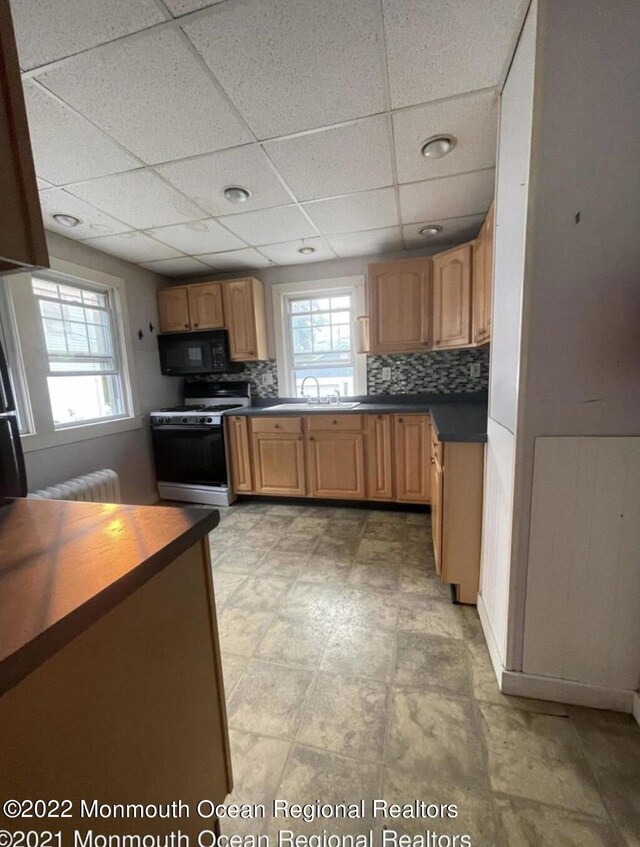 kitchen with backsplash, gas range gas stove, sink, and a drop ceiling