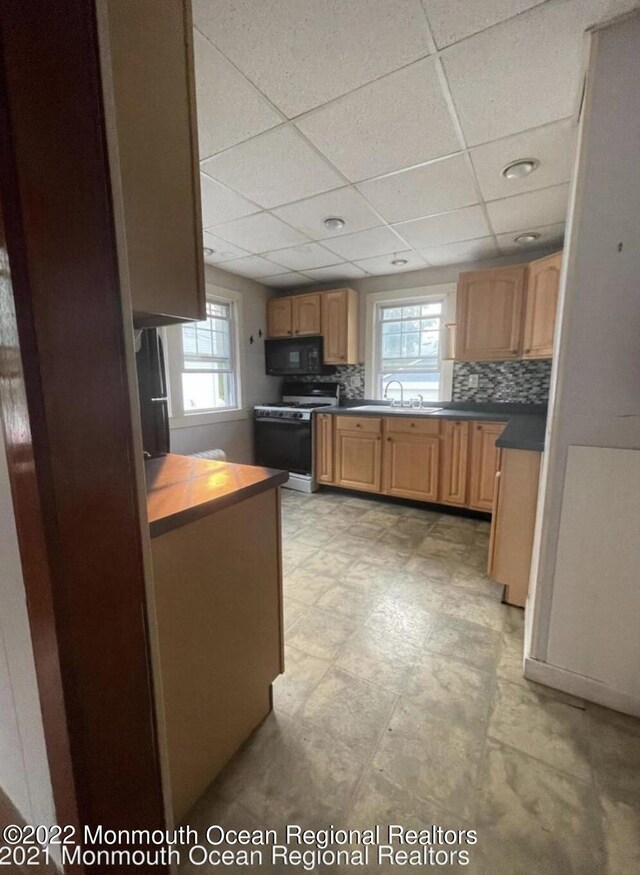 kitchen featuring tasteful backsplash, a healthy amount of sunlight, a paneled ceiling, and gas range oven