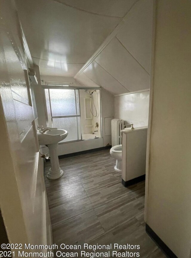 bathroom with vaulted ceiling, an enclosed shower, radiator, hardwood / wood-style floors, and toilet