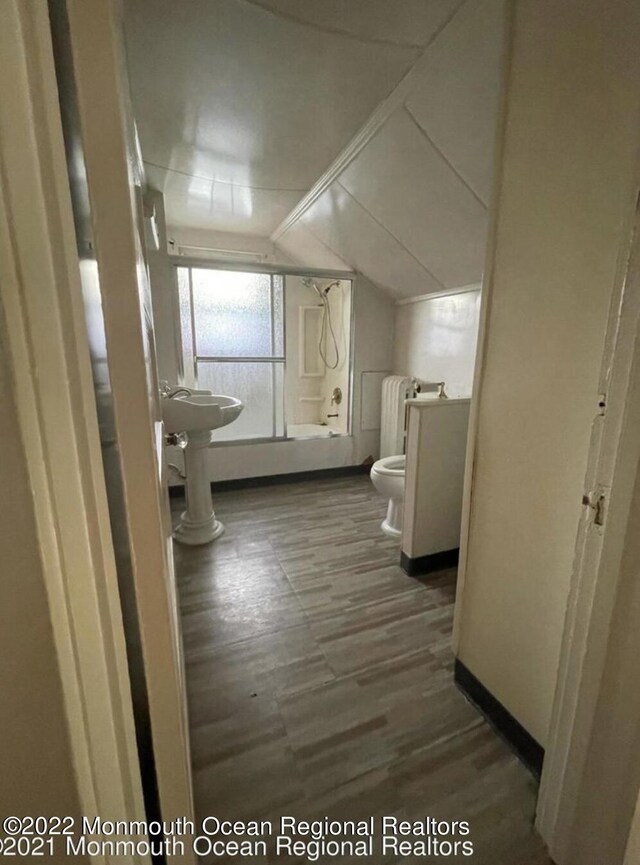 interior space with dark hardwood / wood-style floors, radiator heating unit, and vaulted ceiling